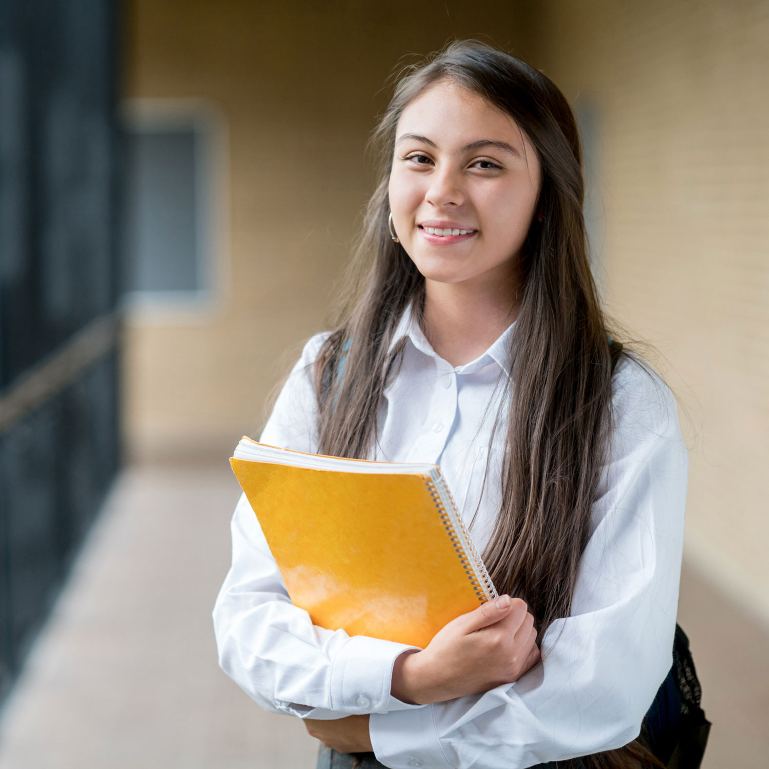 Teen girl standing while holding wire coil notebook