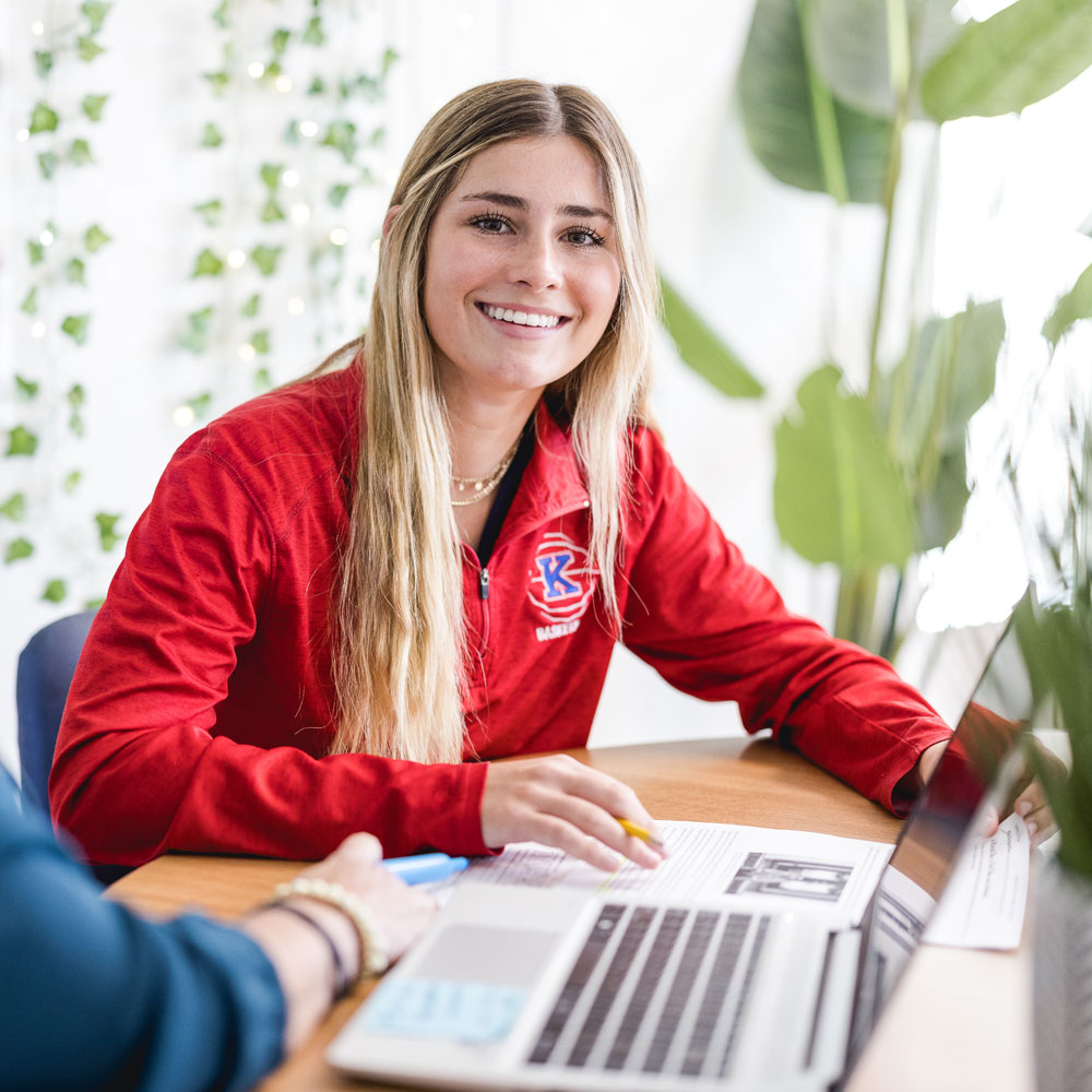 Girl in red sports jacket reading over paper.